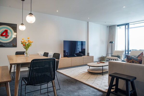 Ein modernes Wohnzimmer mit Essbereich, einem Flachbildfernseher und einem großen Fenster.