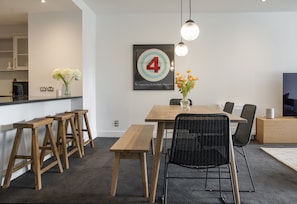 Ein moderner Essbereich mit einem Holztisch, schwarzen Korbstühlen und einem großen Kunstwerk mit der Zahl 4 an der Wand.