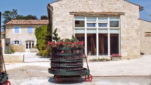 Un edificio de piedra con un gran ventanal y un carrito de flores en la entrada.