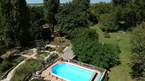 Una piscina rectangular rodeada por una terraza y una valla de madera, con un pequeño cobertizo cerca.