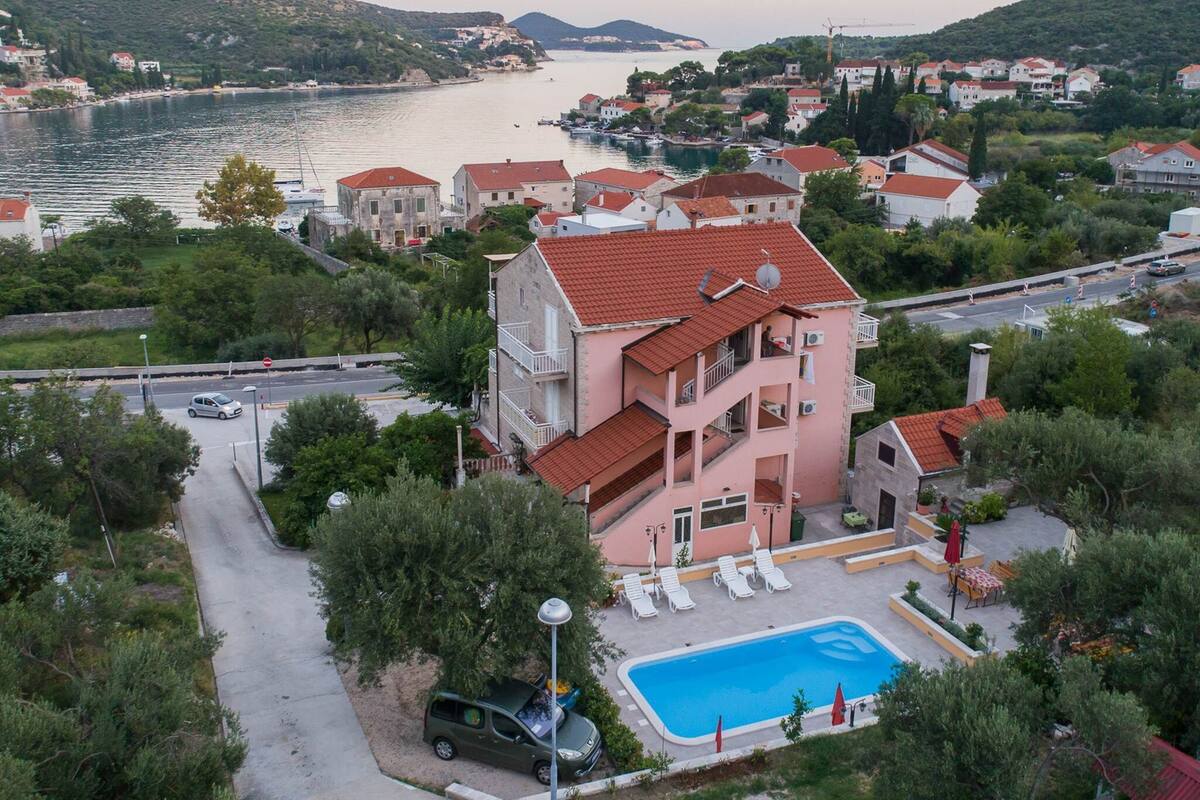Un immeuble à plusieurs étages doté d’une piscine, entouré de verdure et offrant une vue sur la côte.