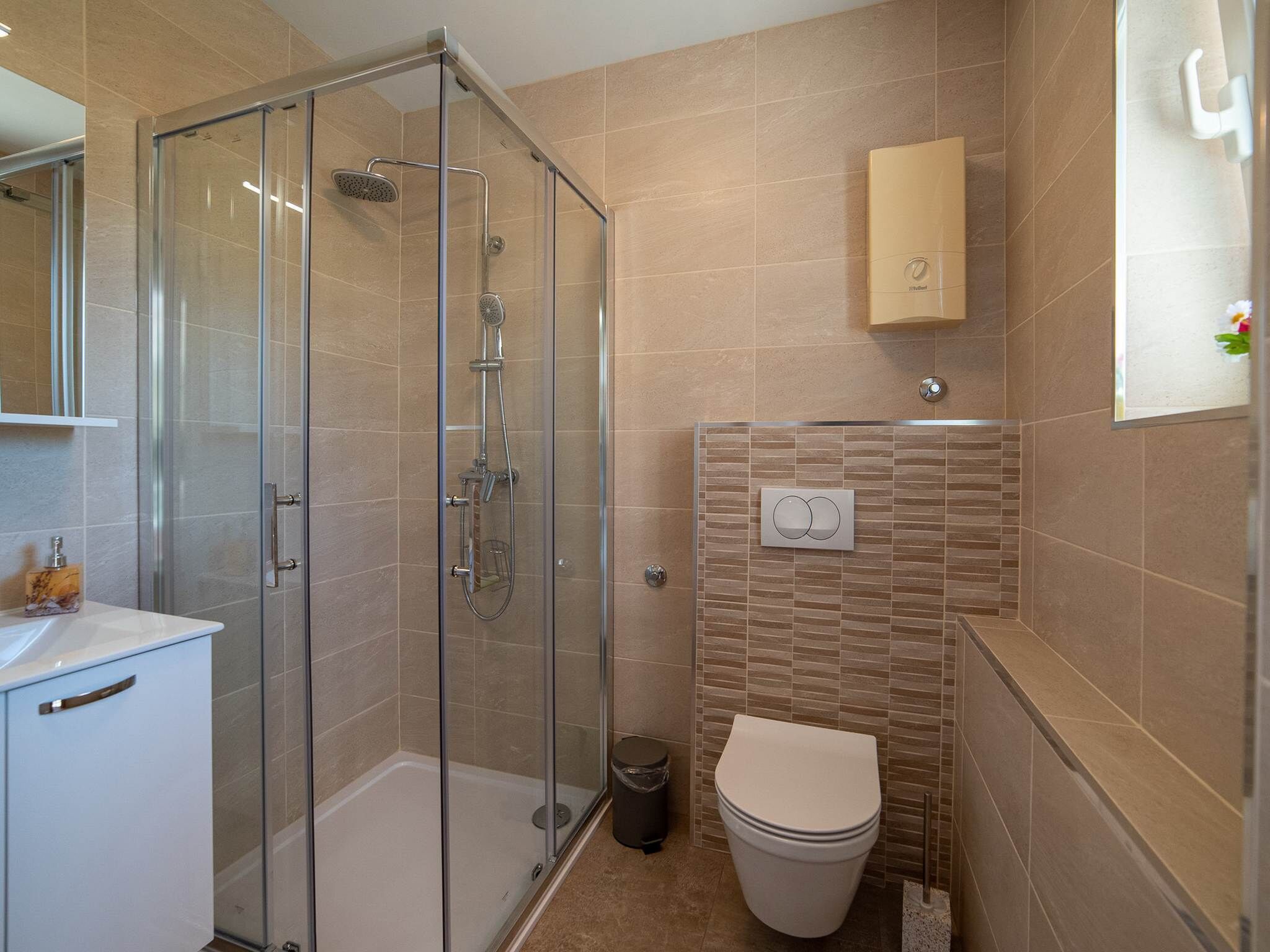 A modern bathroom with a glass-enclosed shower, a toilet, and a sink.