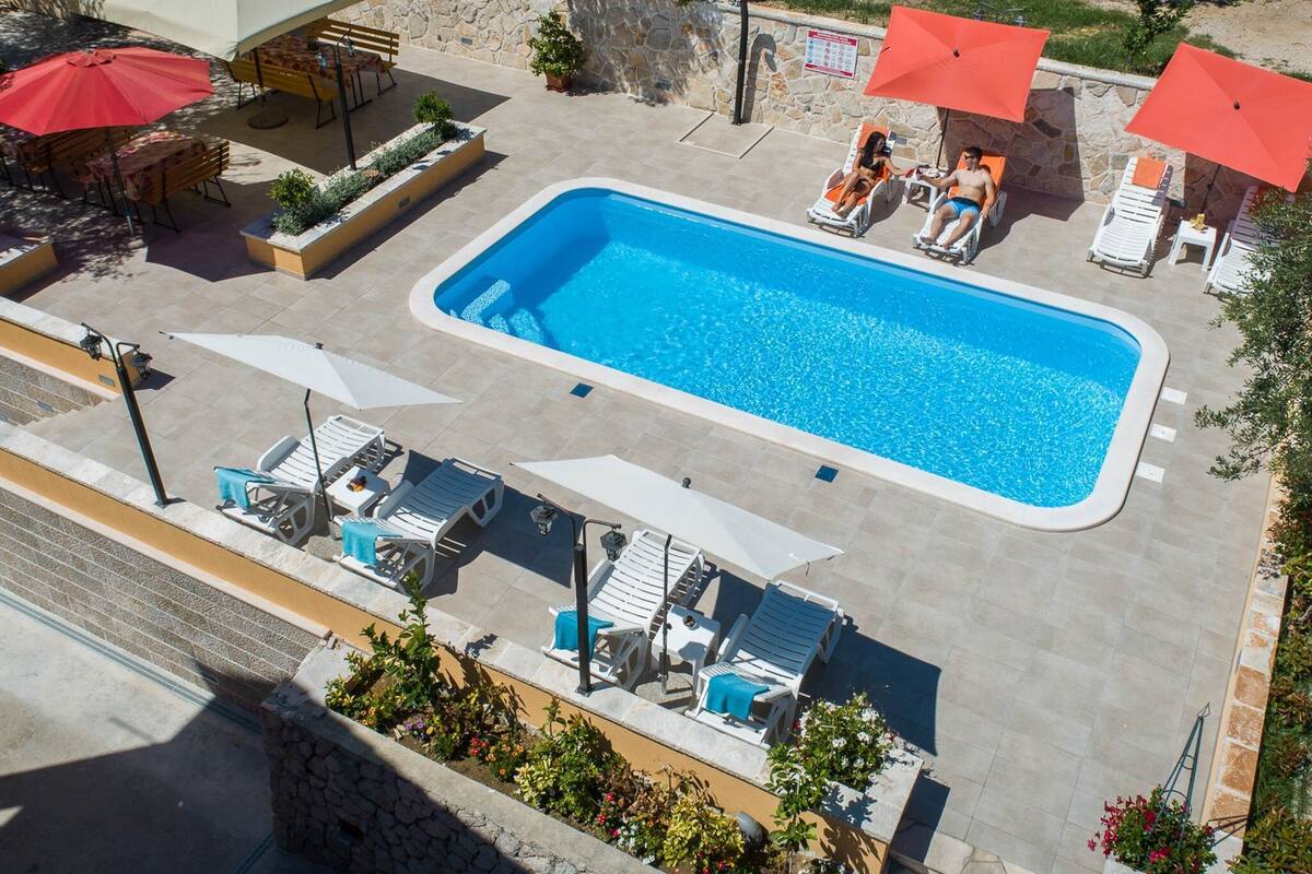 Une piscine rectangulaire entourée de chaises longues et de parasols.