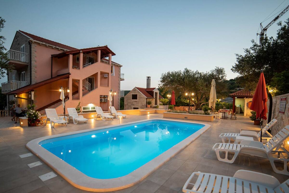 Une piscine avec des chaises longues et un bâtiment doté d’un balcon.