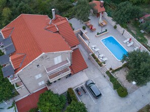 A large house with a red-tiled roof, a swimming pool, and a car parked in the driveway. - Apartments Njirić  (Dubrovnik)
