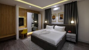 A modern bedroom with a large bed, bedside tables, a desk, and a chair. - George Residence (Lekki)