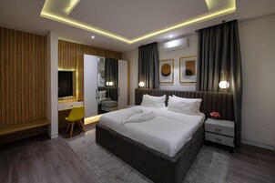 A modern bedroom with a large bed, bedside tables, a desk, and a chair.
