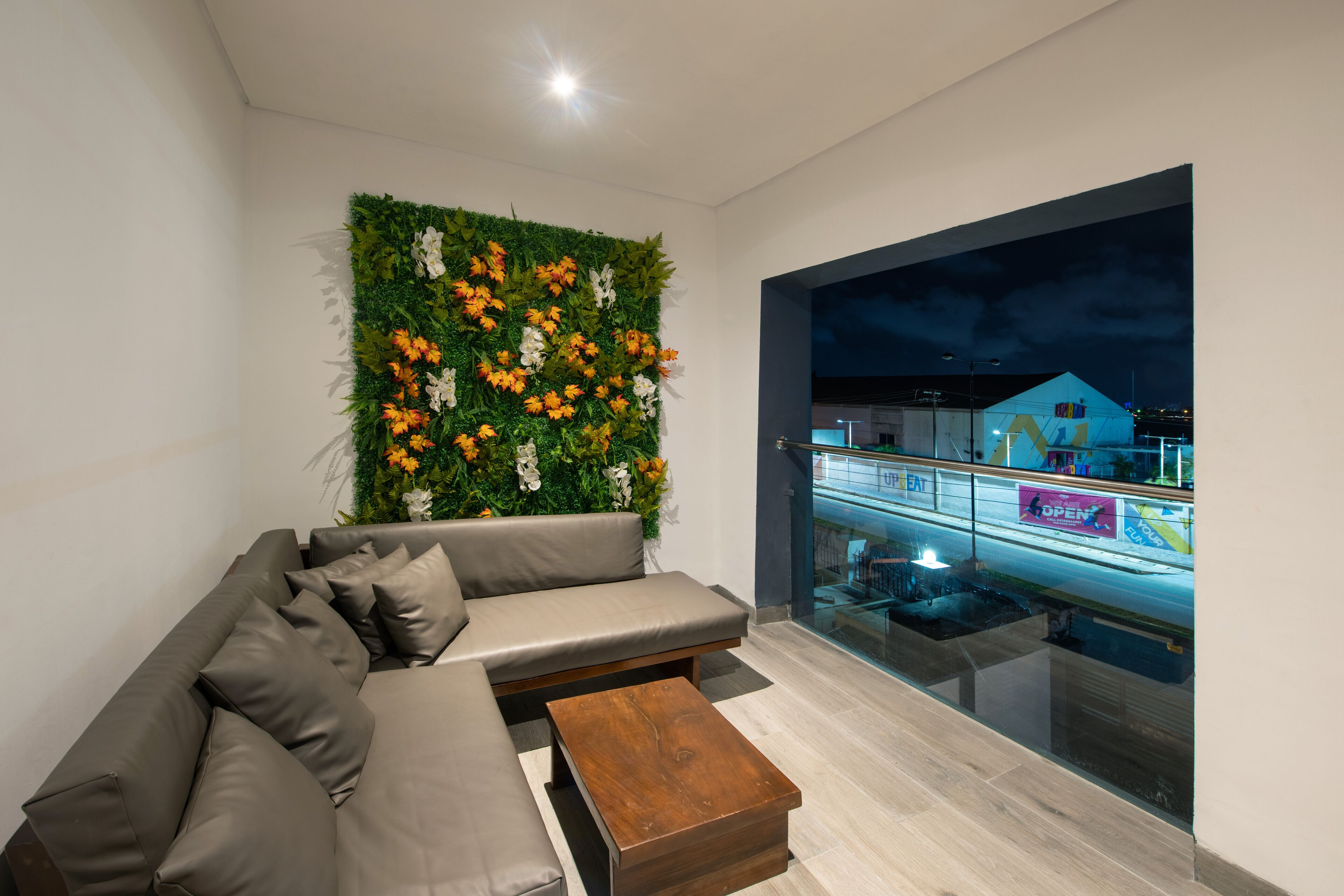 A modern living room with a grey sofa, a wooden coffee table, and a green vertical garden wall.