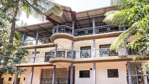 A multi-story building with balconies, a covered walkway, and palm trees. - Rustic Pvt 2bhk Villa w/ Fiber Net - Dar AlSalaam (Pilar)
