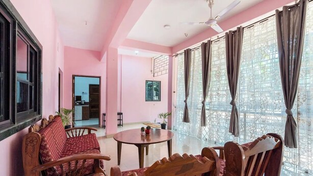 A pink-themed room with a wooden sofa, a round table, and a ceiling fan. - Rustic Pvt 2bhk Villa w/ Fiber Net - Dar AlSalaam (Pilar)