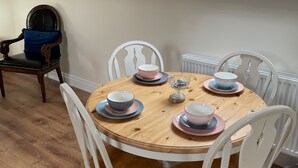 A dining area with a wooden table set for four, surrounded by white chairs.