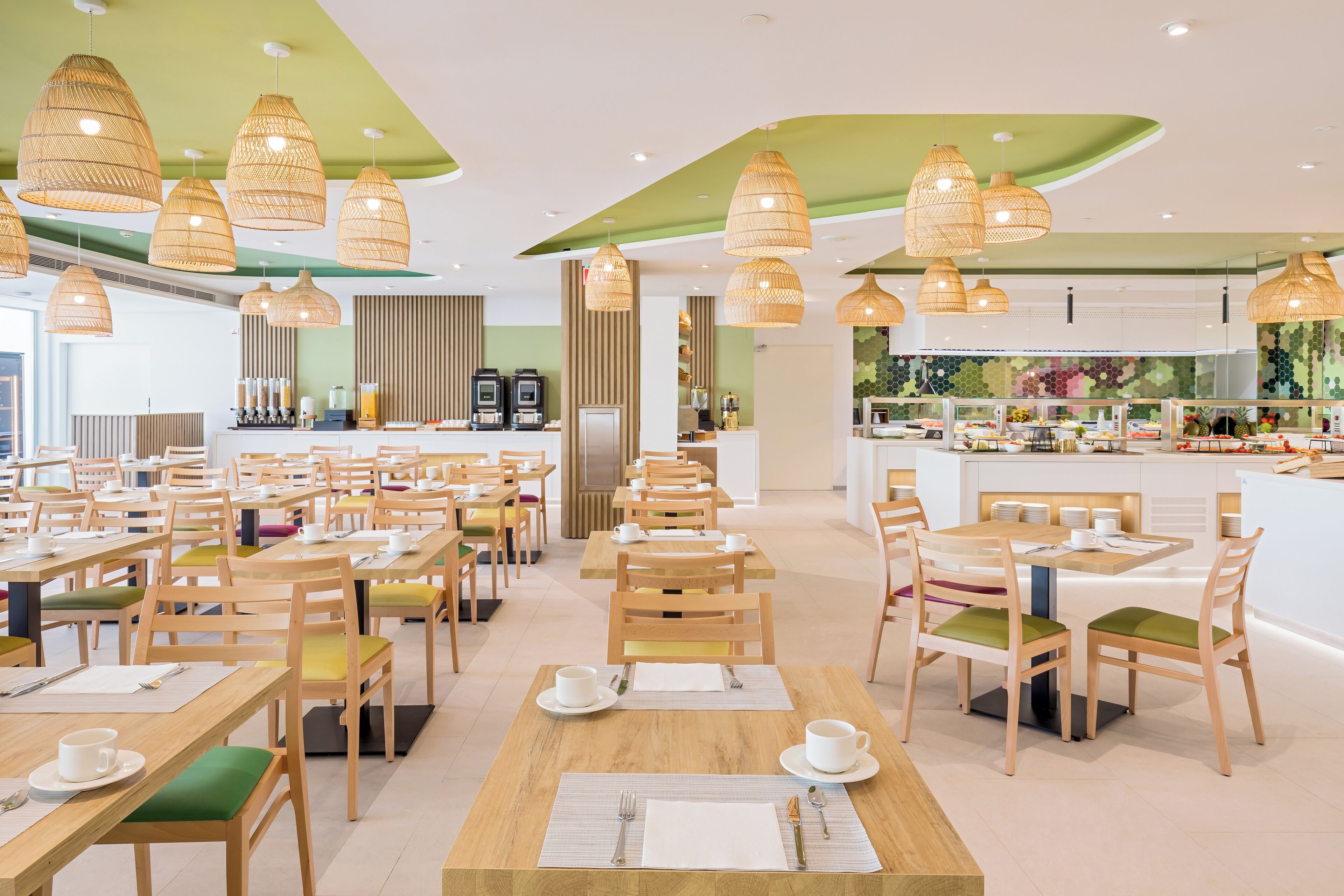 Un restaurante moderno con varias mesas y sillas, una zona de bar y lámparas de mimbre colgantes.