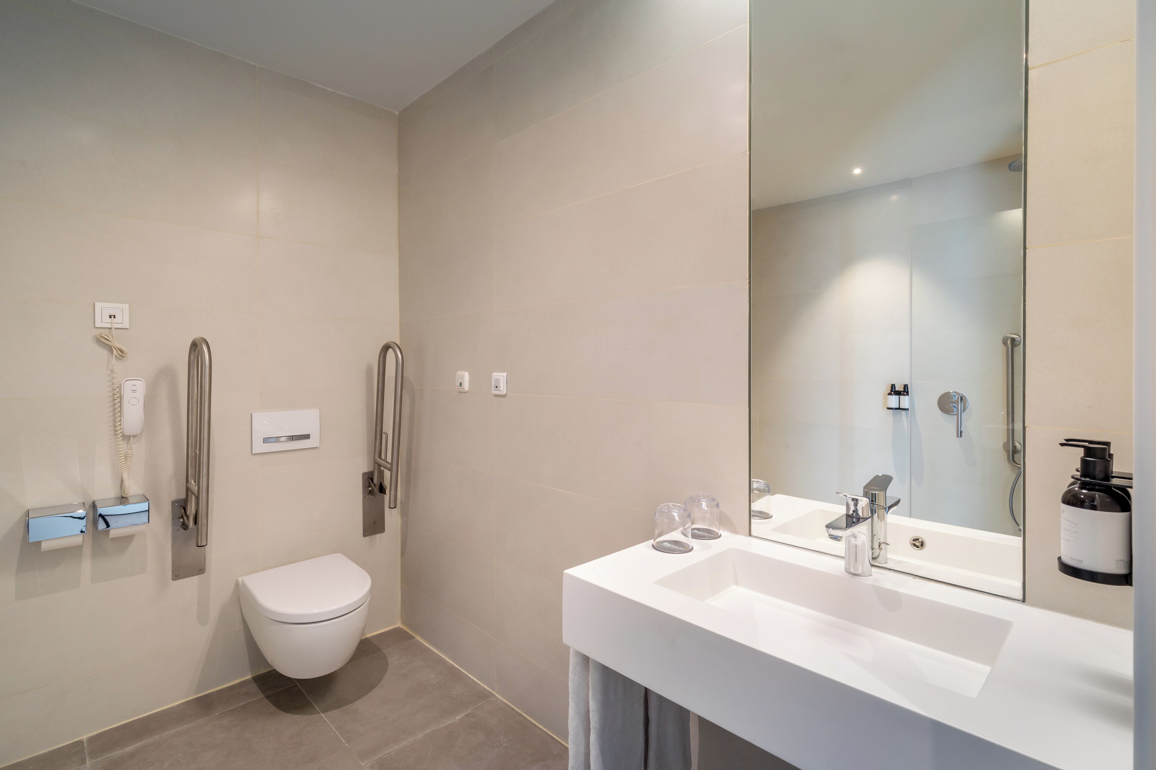 A modern bathroom with a toilet, bidet, and a large mirror above a sink.