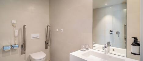 A modern bathroom with a toilet, bidet, and a large mirror above a sink.