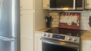 Una cucina con mobili bianchi, frigorifero in acciaio inossidabile, forno a microonde e forno.