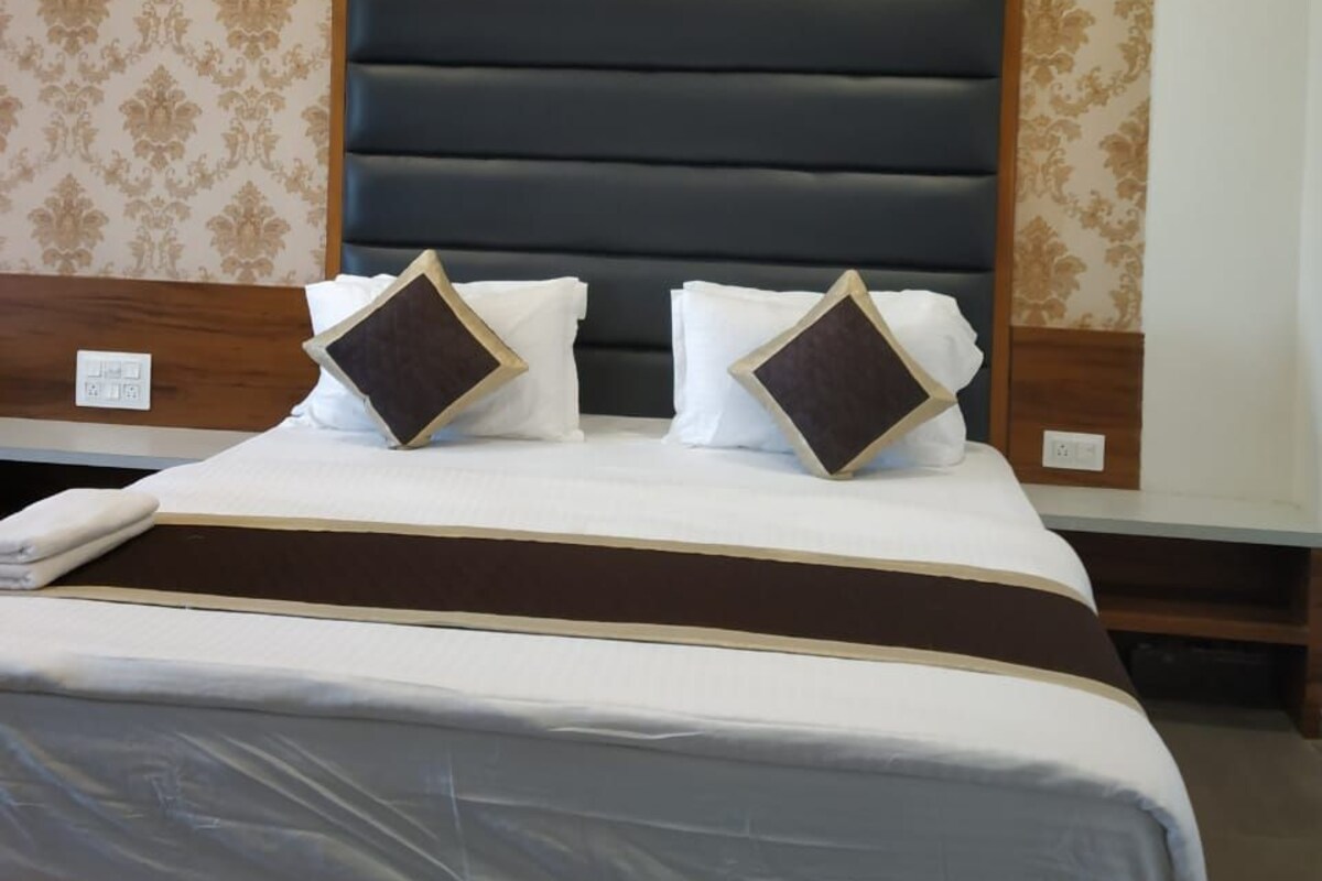 A hotel room with a large bed, a ceiling fan, and patterned wallpaper.