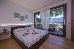 A bedroom with a bed, a nightstand, and a view of the outdoors.