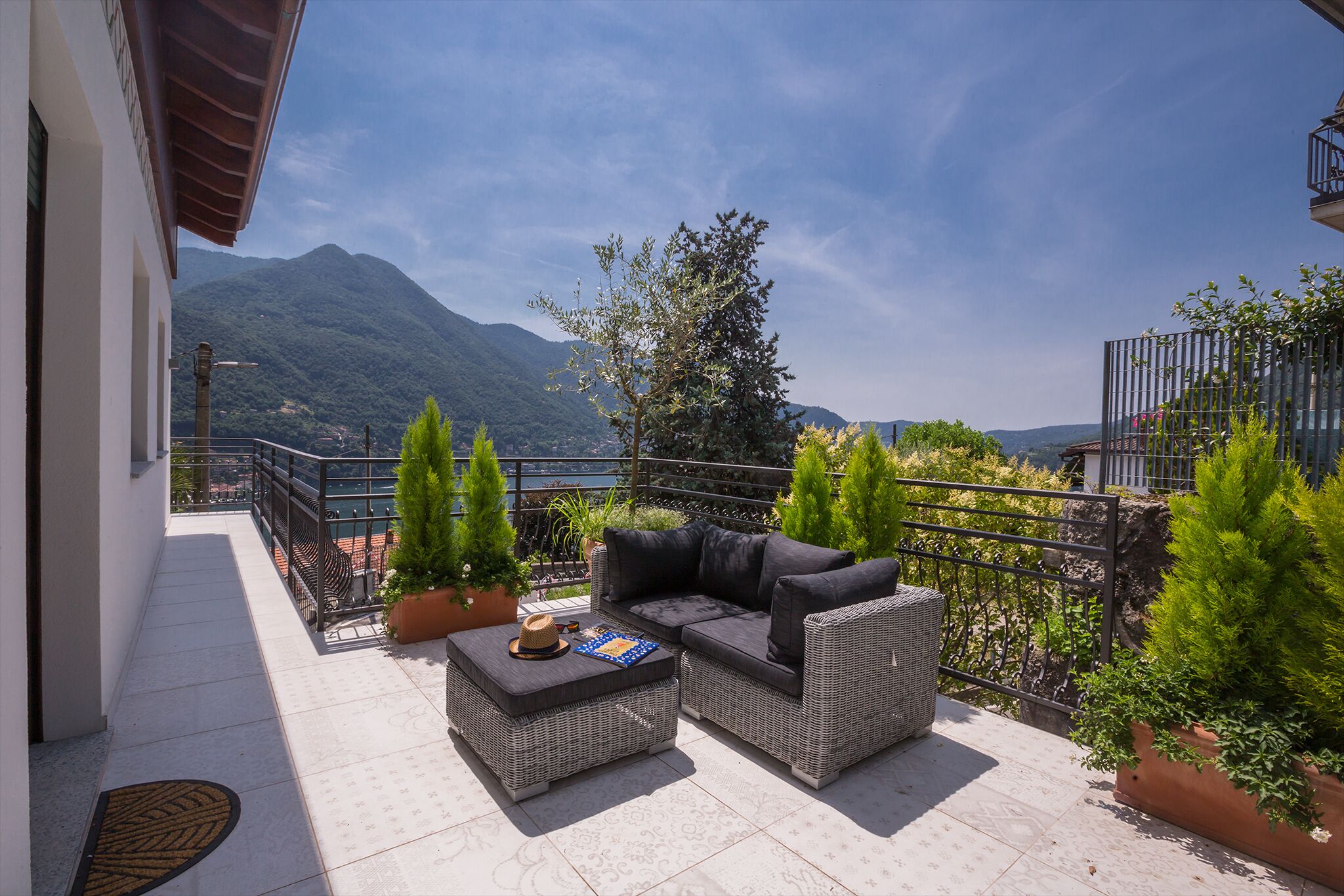 A balcony with wicker furniture, potted plants, and a mountain view.