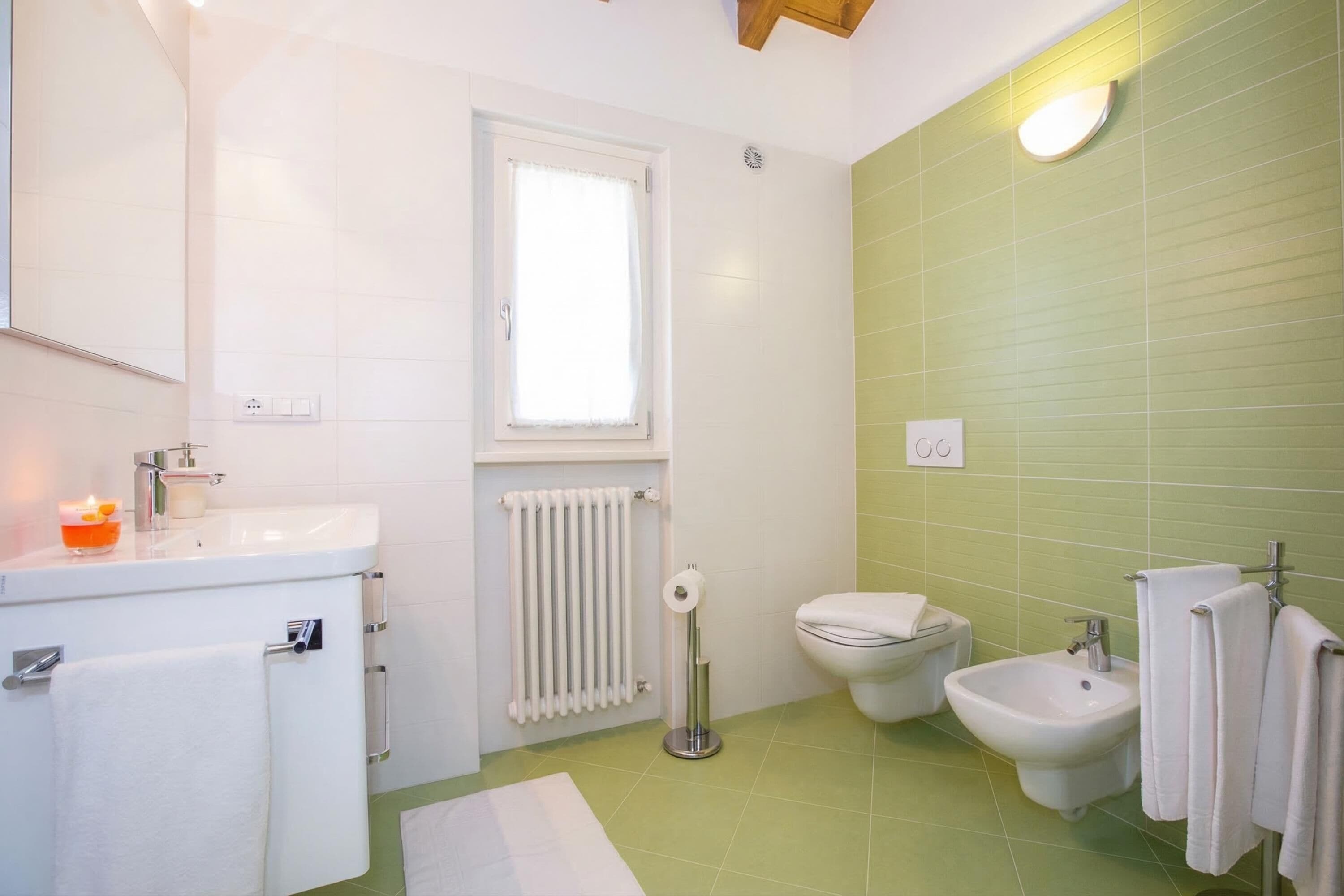 A bathroom with a sink, toilet, bidet, and a window.