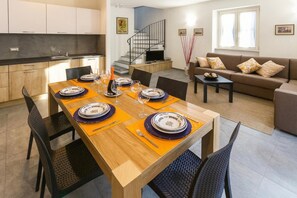 Una cocina moderna con comedor, una escalera y una sala de estar con sofá.