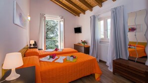 A room with two beds, a wooden ceiling, a TV, a window with curtains, and a radiator. - Lenno Dolcelago (Tremezzina)