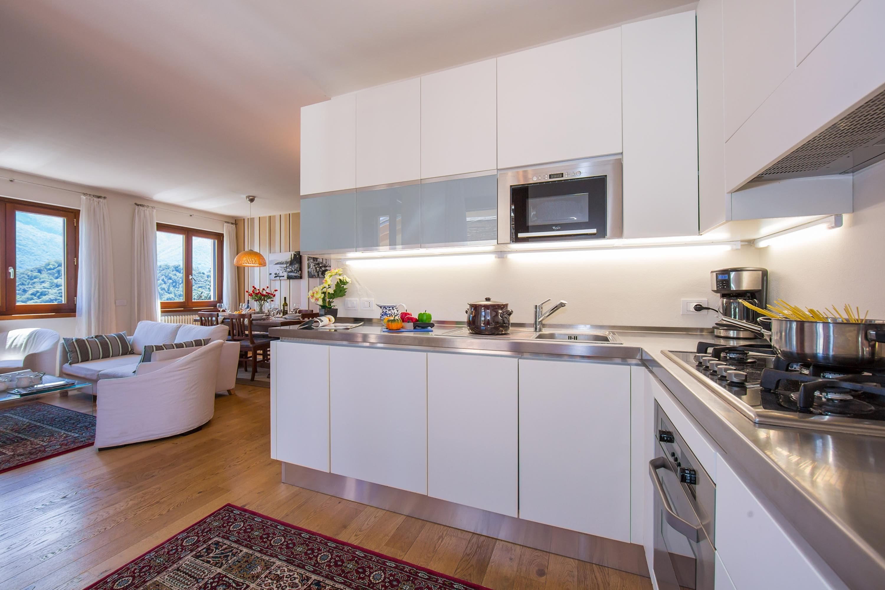A modern kitchen with white cabinetry, a built-in oven, and a stove.