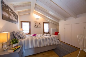 Quarto com cama, mesa de cabeceira, luminária e janela.