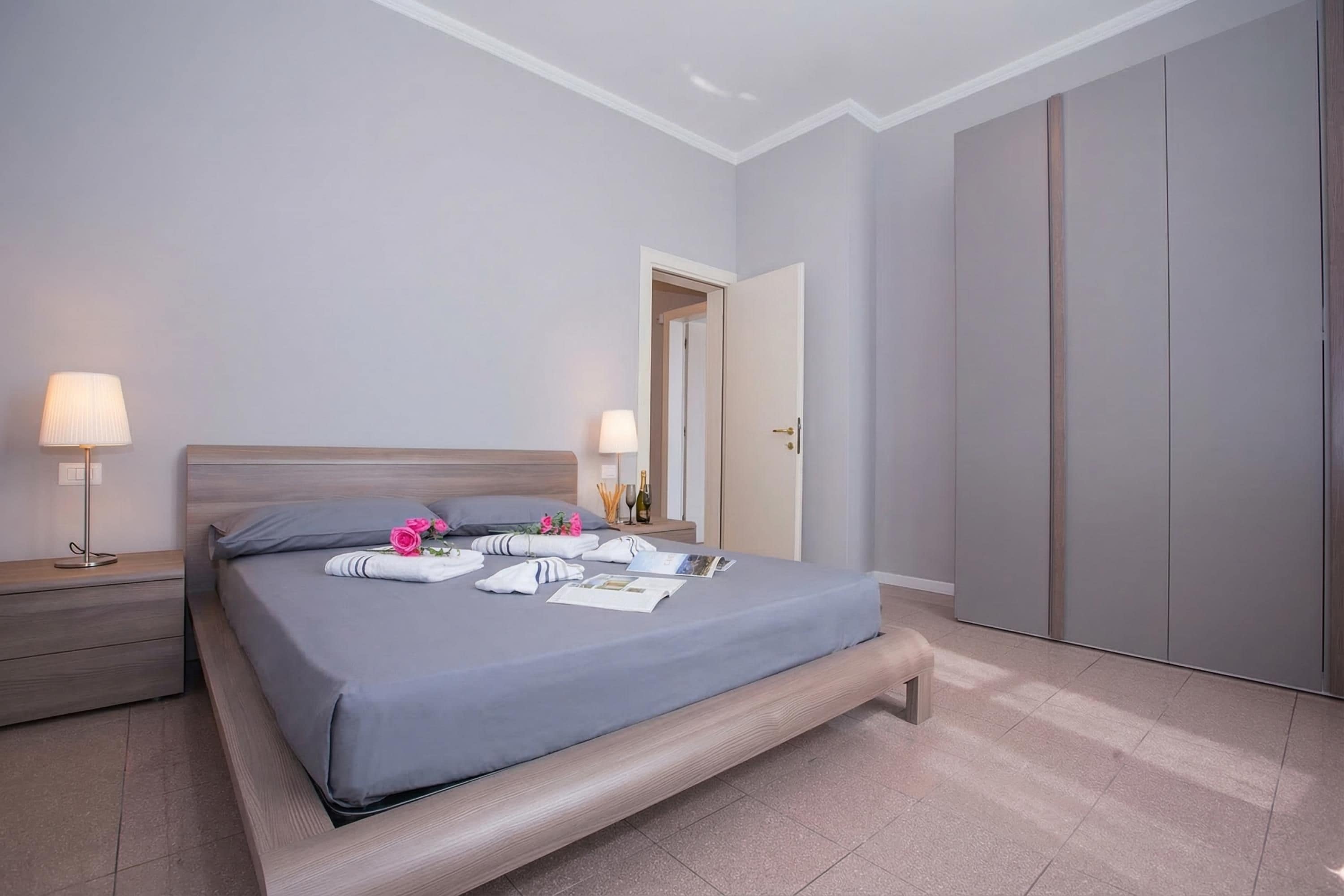 Una camera da letto moderna con un letto, comodini, un armadio e una porta.