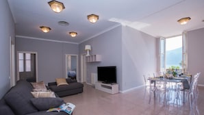 A modern living room with a sofa, TV, dining table, and chairs. - Casa Daniele (Menaggio)