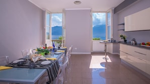 A modern kitchen with a dining area, large windows with a view of the sea, and a balcony. - Casa Daniele (Menaggio)