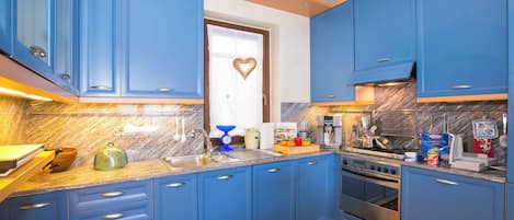 A kitchen with blue cabinets, a stove, and various kitchen appliances.
