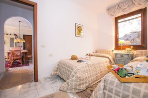 Une chambre à coucher avec un lit, une table de chevet avec une lampe, une fenêtre et une porte donnant sur une autre pièce.