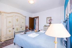 A bedroom with a bed, a wardrobe, a lamp, and a door leading to another room. - Veranda di Menaggio (Menaggio)