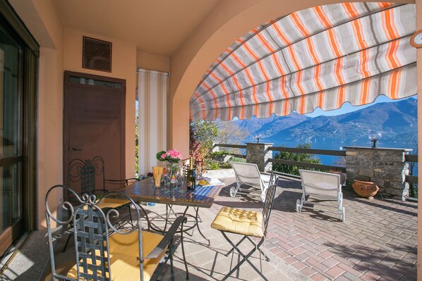 Une terrasse extérieure avec une table dressée pour le repas, une chaise et une vue sur les montagnes.