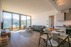 A modern living space with a large sliding glass door leading to a balcony with a scenic mountain view. - Penthouse-LakeView-AC-PrivateGarden (Menaggio)