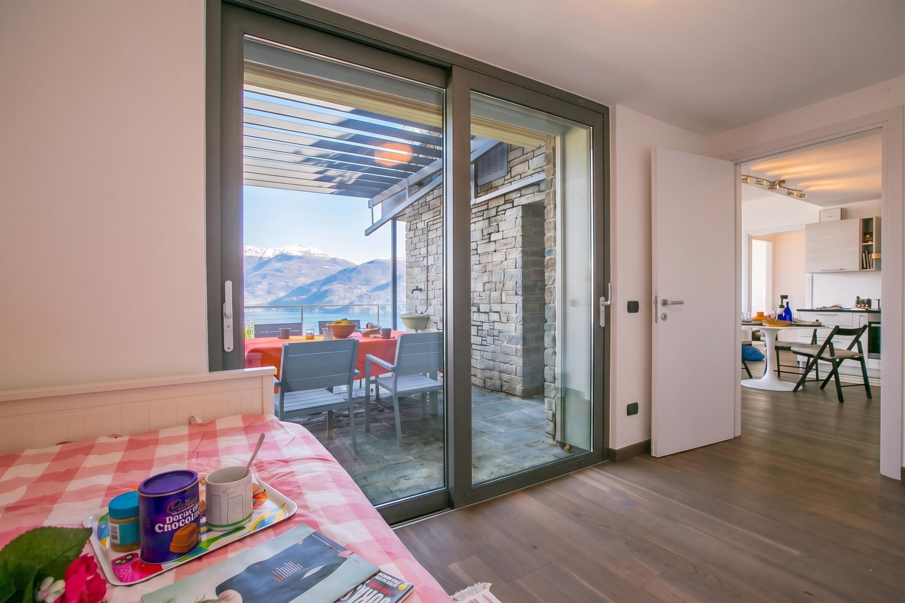 A modern room with a sliding glass door leading to a balcony with a mountain view.