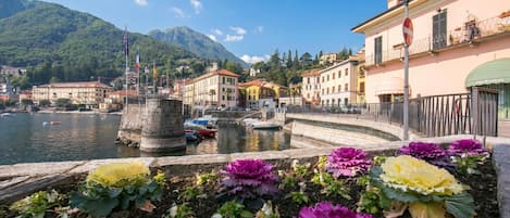 A waterfront view with buildings, a stone structure, and colorful flowers.