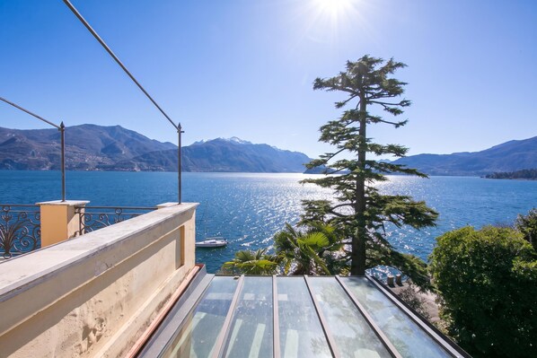 A balcony with a view of a lake, mountains, and a clear sky.