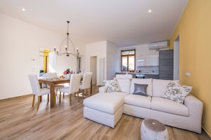 Una sala de estar moderna con comedor, un sofá y una cocina al fondo.