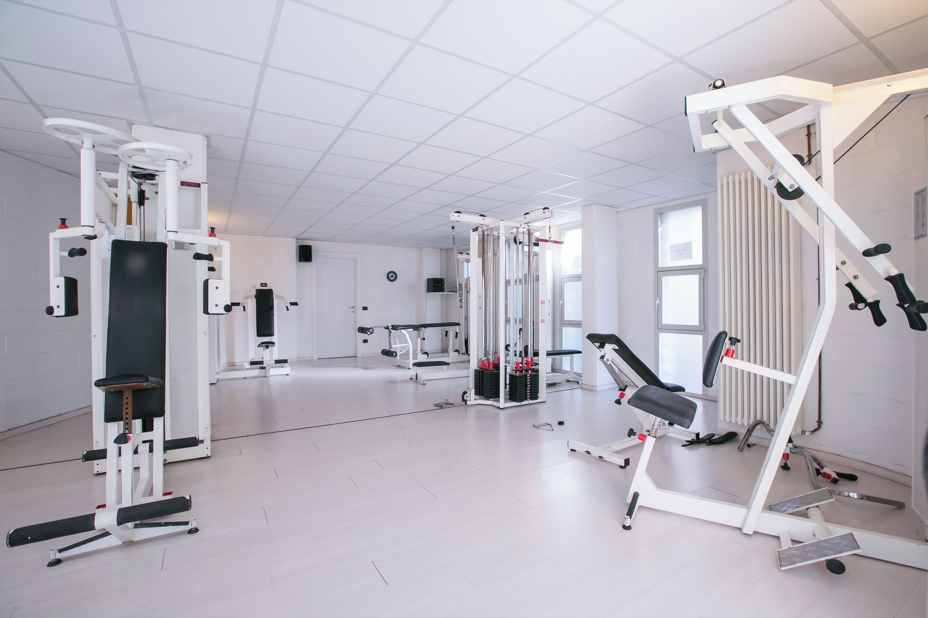 Un gimnasio con diferentes equipos de ejercicio, un espejo grande y una ventana.