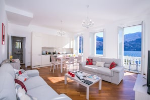 A modern living room with a sofa, coffee table, and a dining area with chairs. - Villa Larius Balcone (Carate Urio)
