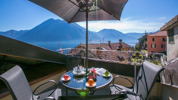 Una mesa con sombrilla, sillas y vistas a montañas y edificios.