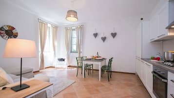 Una cocina moderna con armarios blancos, una mesa de comedor con sillas, una lámpara y un reloj en la pared.