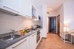 Una cocina moderna con un lavamanos de acero inoxidable, armarios blancos y salpicadero de azulejos.