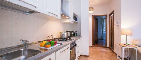 A modern kitchen with a stainless steel sink, white cabinets, and a tiled backsplash.