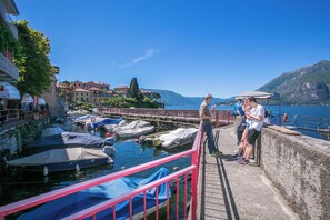 A marina with boats docked, a bridge, and buildings in the background. - Casa Al Prato Apt. B (Varenna)