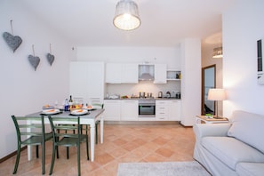 Una cocina moderna con armarios blancos, una mesa de comedor con sillas y un sofá en la sala.