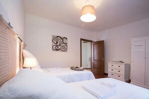 A hotel room with two beds, a bedside table with a lamp, a wall art piece, a dresser, and a door labeled 'Deaville'. - Casa Al Prato Apt. B (Varenna)