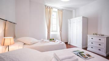 Ein Hotelzimmer mit zwei Betten, einem Schrank, einer Lampe und einem fenster mit Vorhängen.