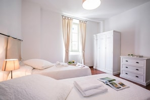 Une chambre d’hôtel avec deux lits, une armoire, une lampe et une fenêtre avec des rideaux.